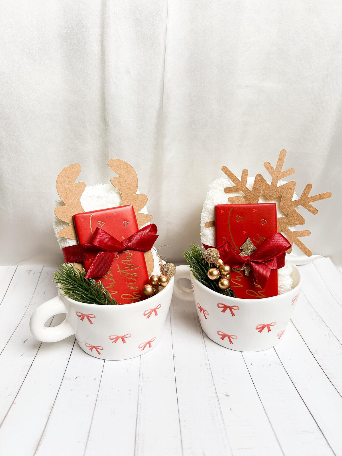 Weihnachtliches Geschenkset in Cremeweiß, Rot und Gold mit Tassen, Schleifen und festlichen Dekoelementen.