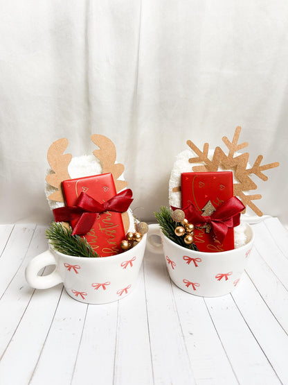 Weihnachtliches Geschenkset in Cremeweiß, Rot und Gold mit Tassen, Schleifen und festlichen Dekoelementen.