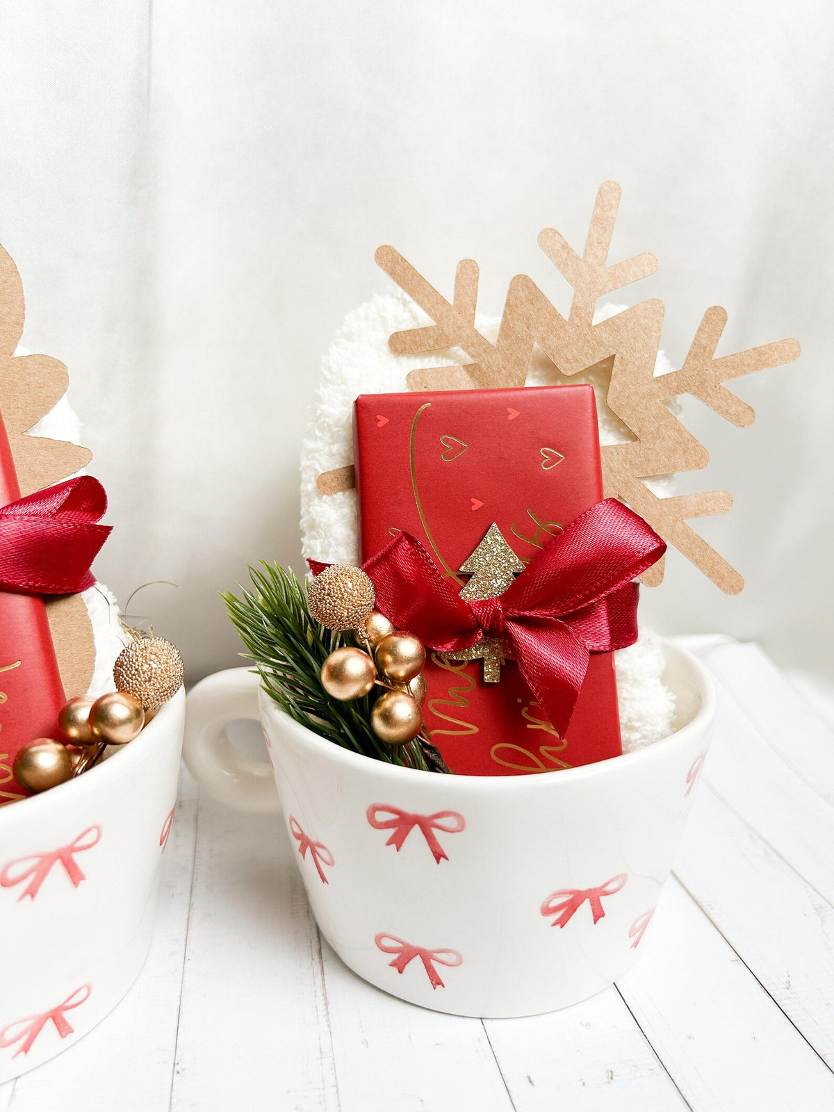 Weihnachtliches Geschenkset in Cremeweiß, Rot und Gold mit Tassen, Schleifen und festlichen Dekoelementen.